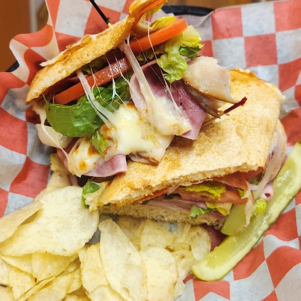Grace's Place Pizzeria's hot sub sandwich with melted cheese, ham, lettuce, tomato, chips, and a pickle.